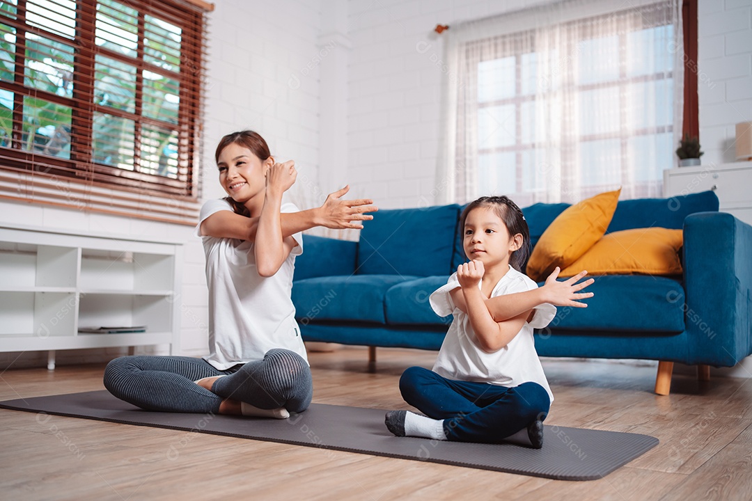 Mãe e filha se exercitando juntas e felizes em casa.