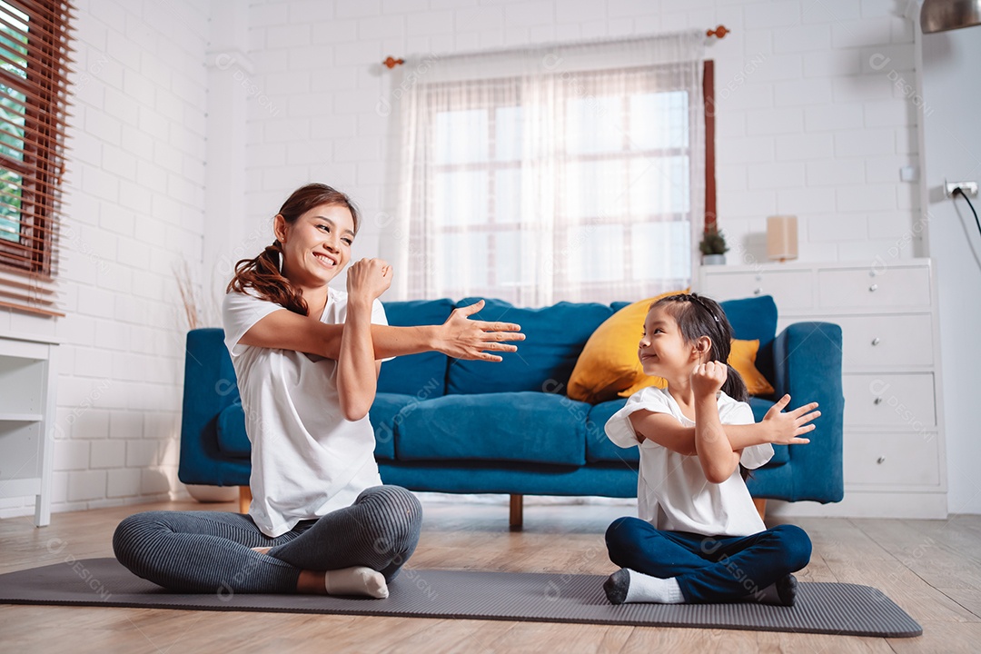 Mãe e filha se exercitando juntas e felizes em casa.