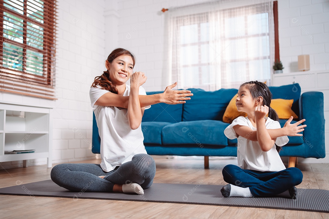 Mãe e filha se exercitando juntas e felizes em casa.