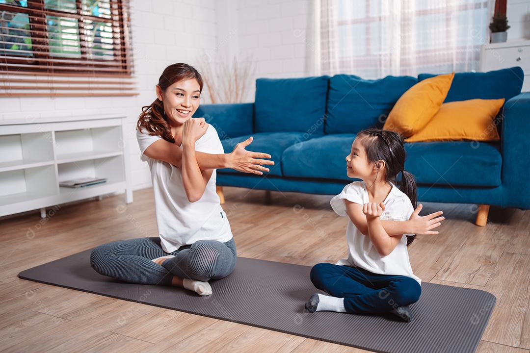 Mãe e filha se exercitando juntas e felizes em casa.