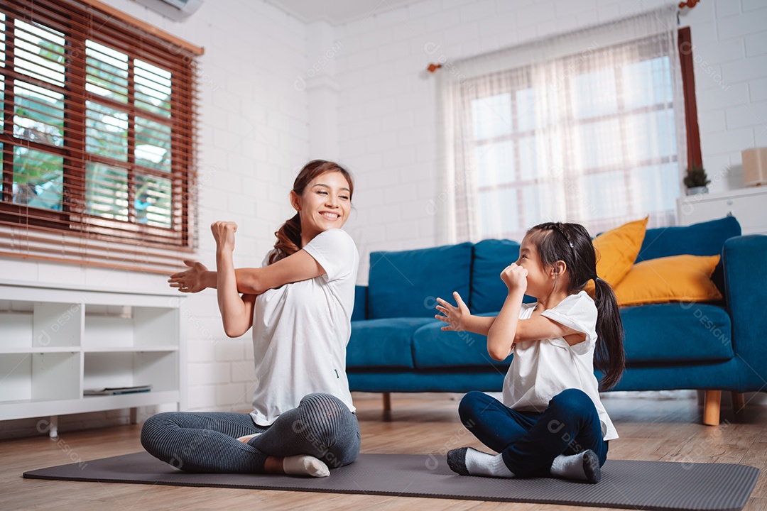 Mãe e filha se exercitando juntas e felizes em casa.