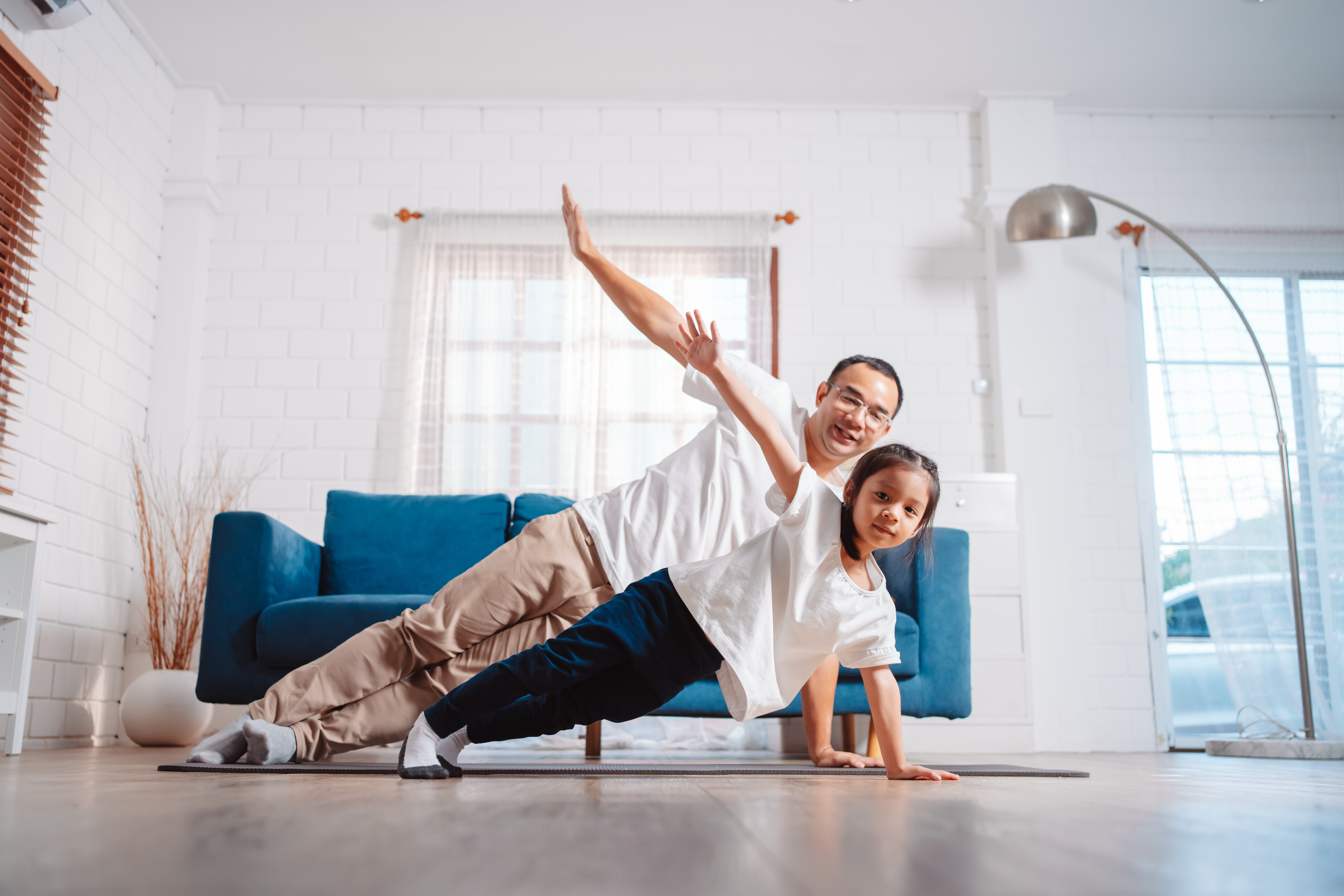 Pai e filha se exercitando juntos e felizes em casa.