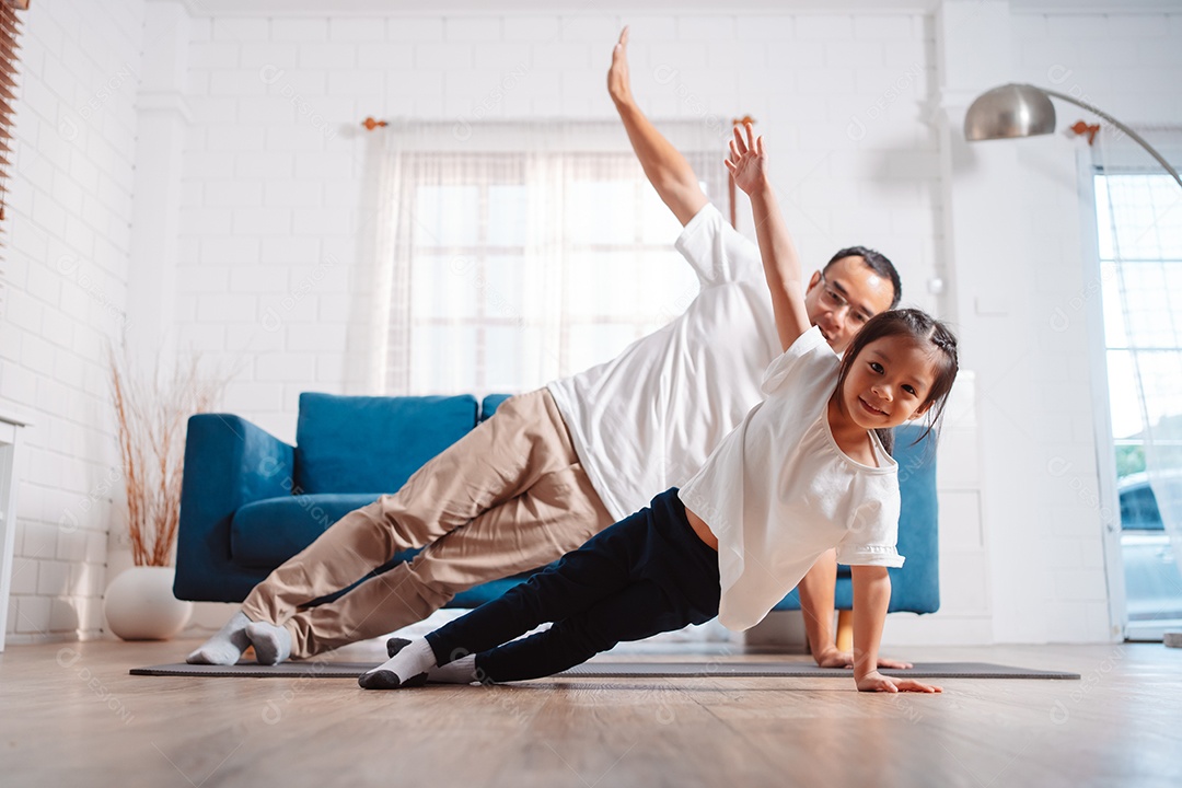Pai e filha se exercitando juntos e felizes em casa.