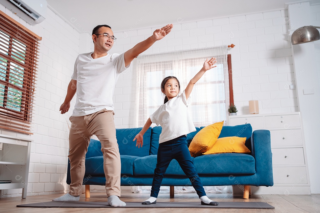 Pai e filha se exercitando juntos e felizes em casa.