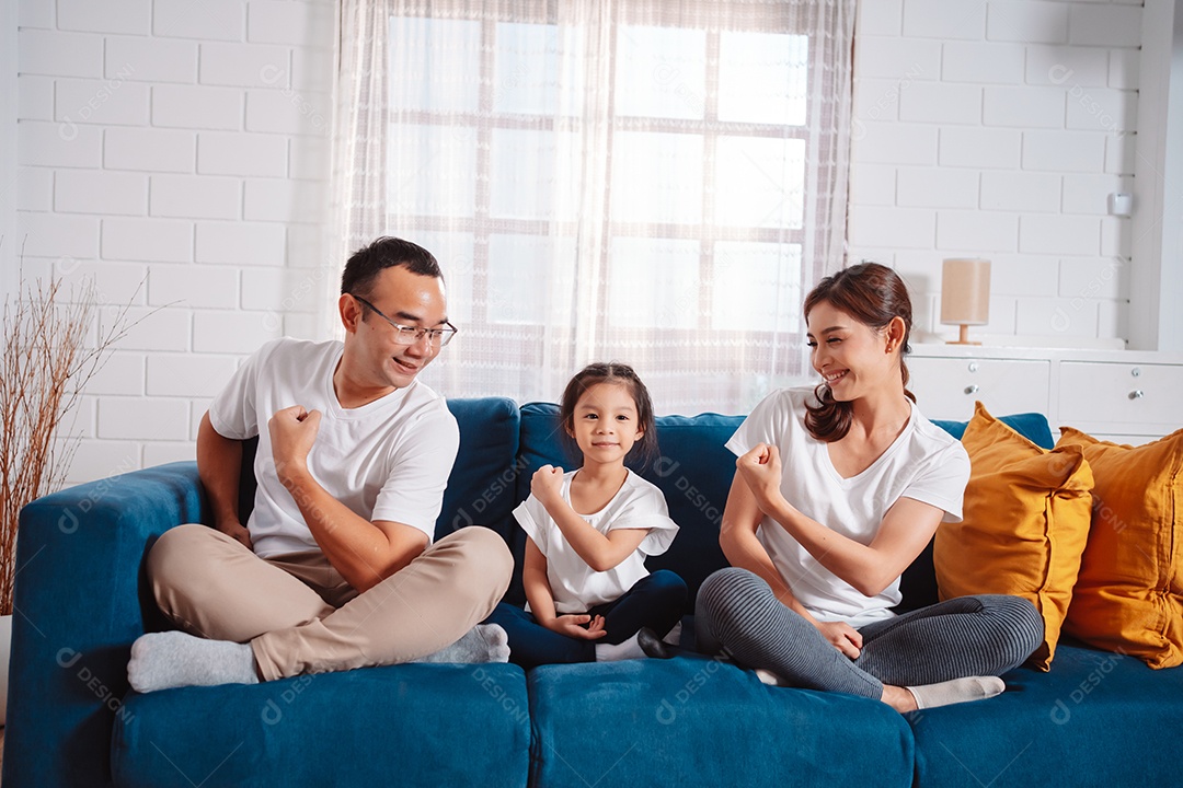 Família composta por pais e filhas se exercitando juntos em casa.