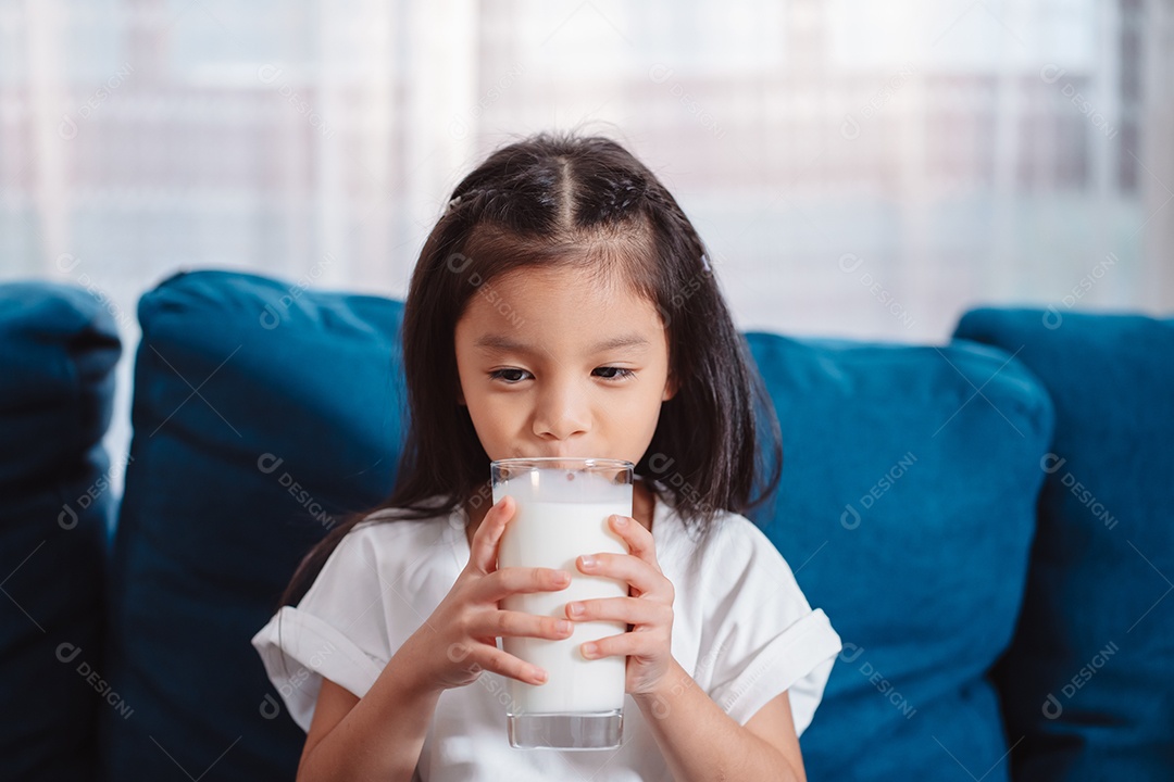 Linda garota asiática bebendo leite em casa para nutrir dentes saudáveis ​​e fortes com vitamina.