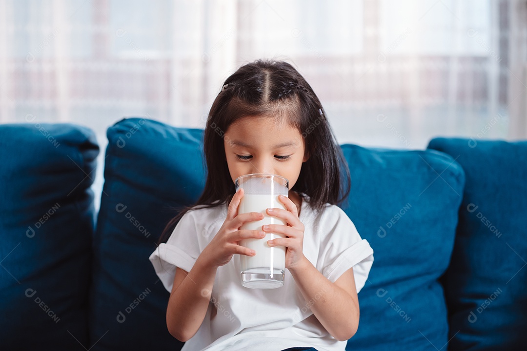Linda garota asiática bebendo leite em casa para nutrir dentes saudáveis ​​e fortes com vitamina.