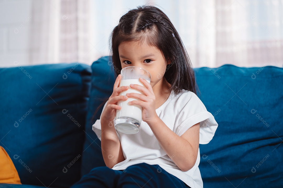 Linda garota asiática bebendo leite em casa para nutrir dentes saudáveis ​​e fortes com vitamina.