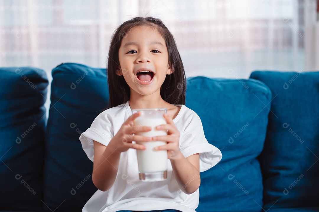 Linda garota asiática bebendo leite em casa para nutrir dentes saudáveis ​​e fortes com vitamina.