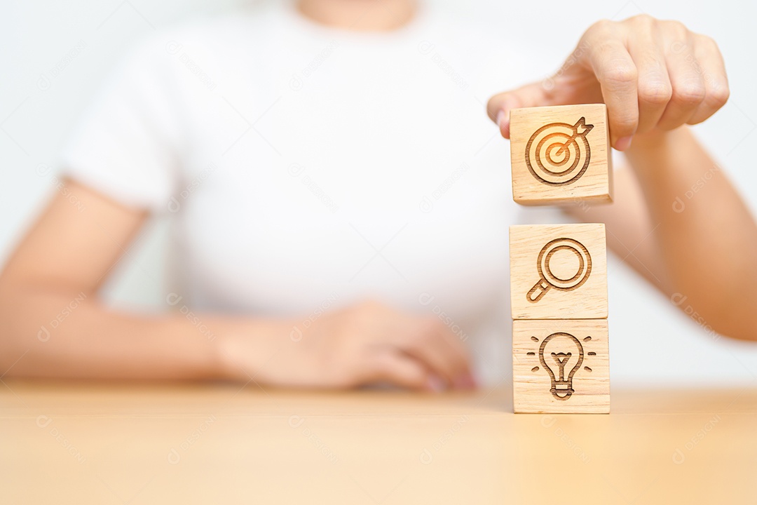 Mão de uma mulher segurando o alvo de dardos acima do bloco de ícones Gear, ampliação e lâmpada.