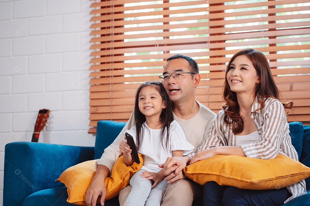 Família asiática composta por pais, filho feliz e filha assistindo TV ou filme juntos no sofá na sala de estar em casa.