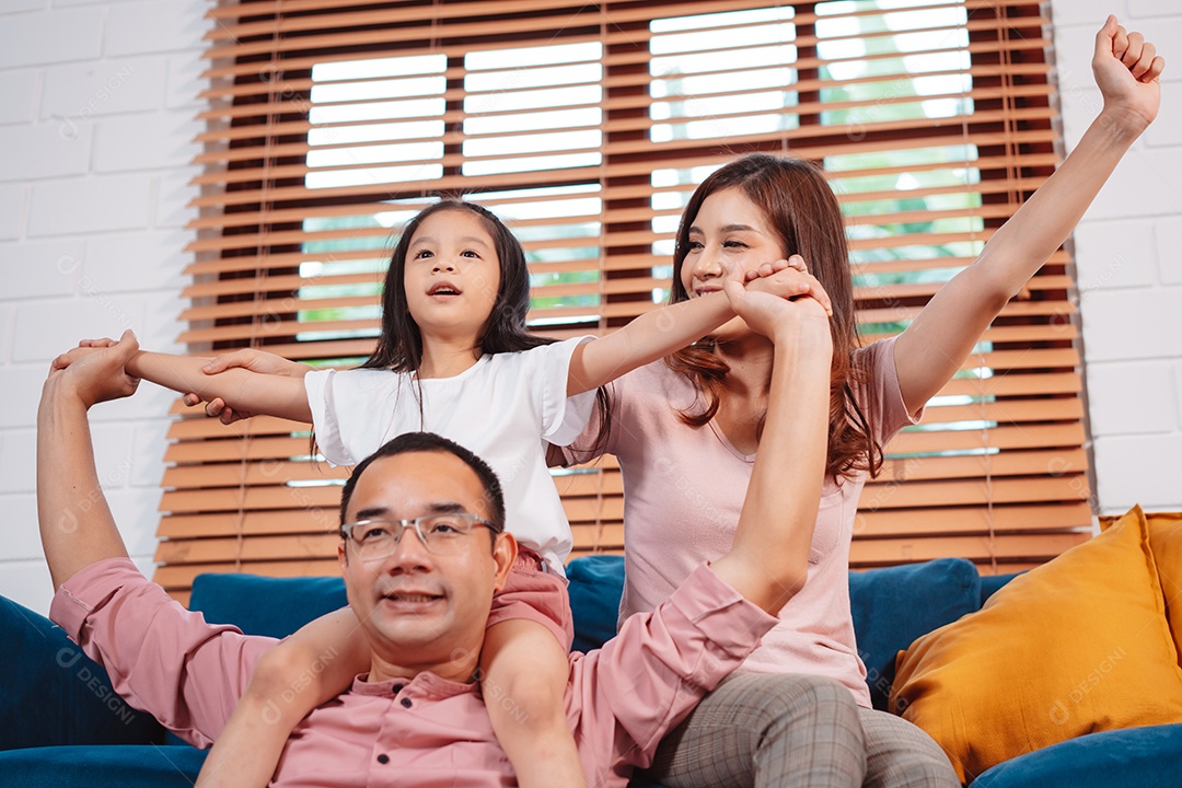Feliz família asiática aproveitando o fim de semana relaxa no sofá brincando juntos em casa.