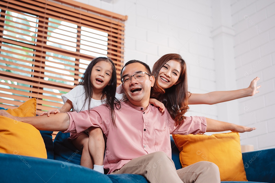 Feliz família asiática aproveitando o fim de semana relaxa no sofá brincando juntos em casa.