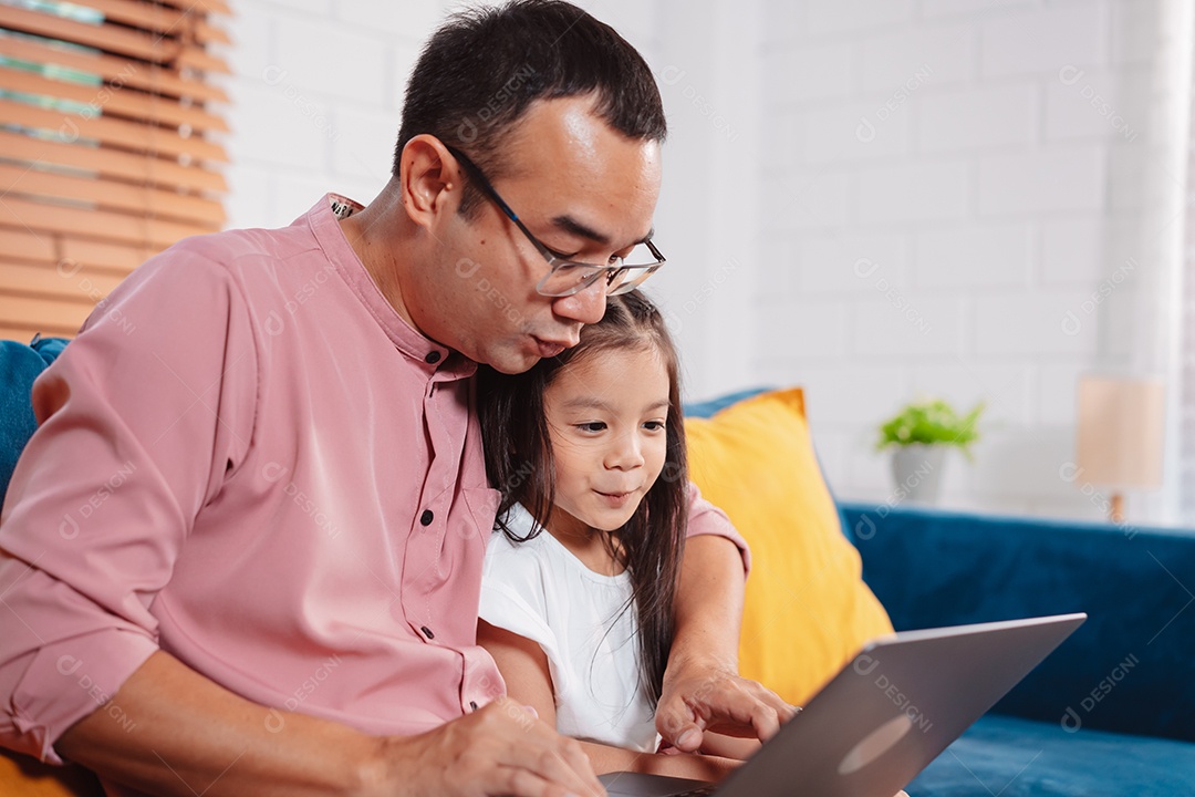 Filha asiática bonitinha com o pai trabalhando no laptop em casa.