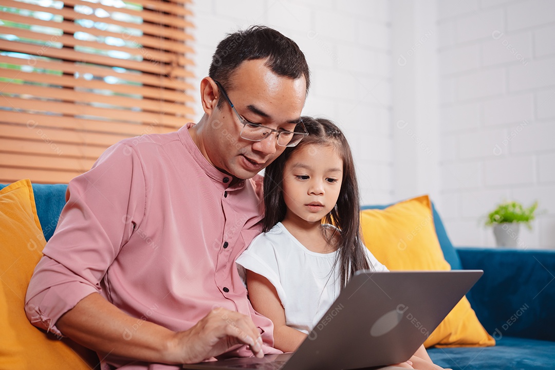 Filha asiática bonitinha com o pai trabalhando no laptop em casa.