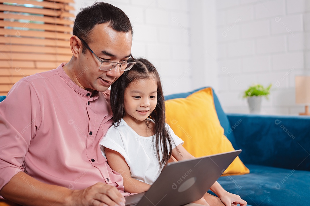 Filha asiática bonitinha com o pai trabalhando no laptop em casa.