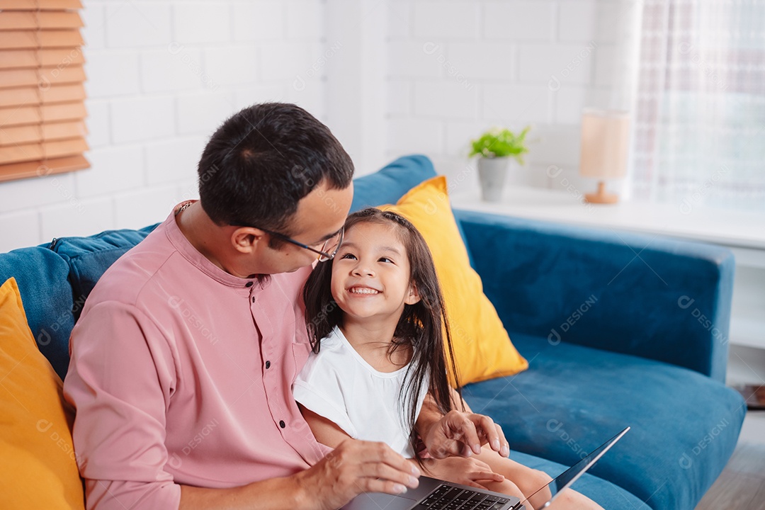 Filha asiática bonitinha com o pai trabalhando no laptop em casa