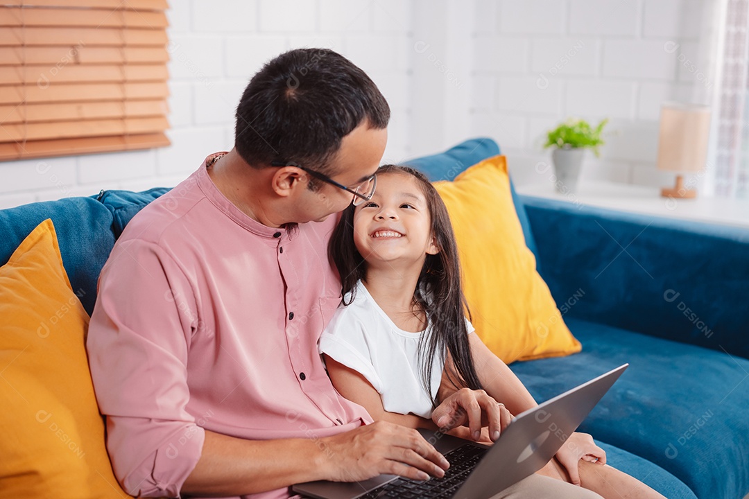 Filha asiática bonitinha com o pai trabalhando no laptop em casa