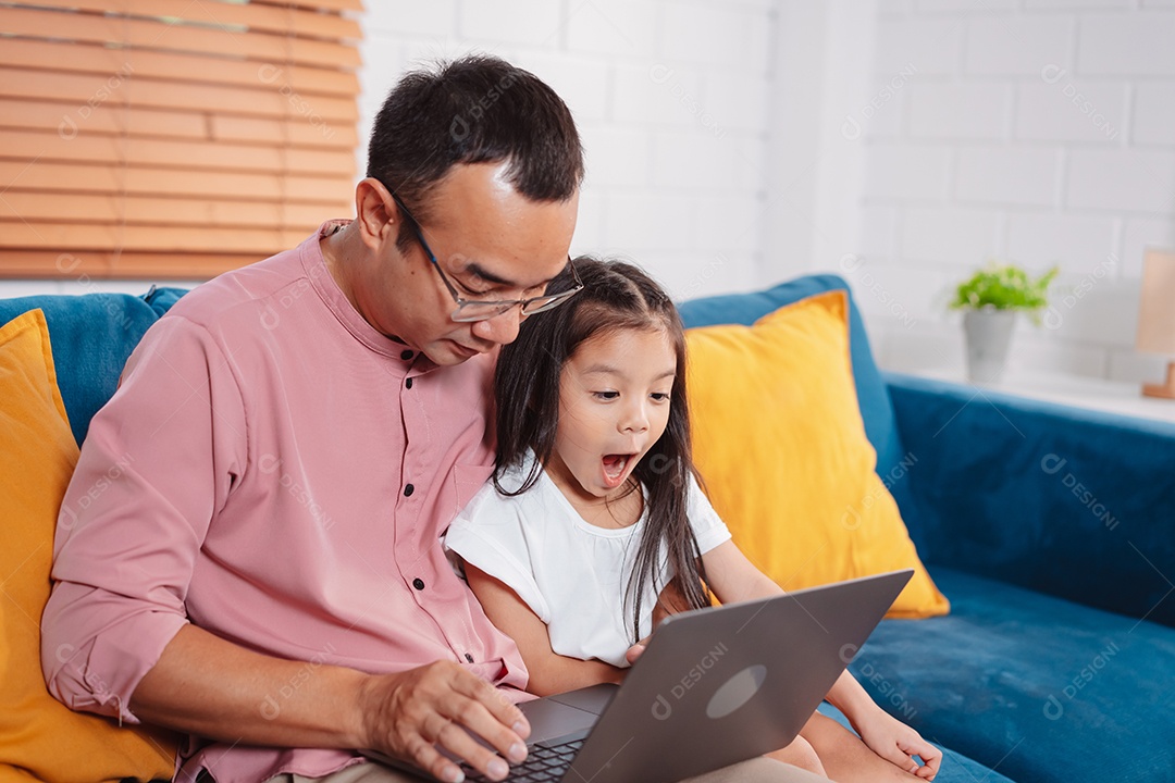 Filha asiática bonitinha com o pai trabalhando no laptop em casa