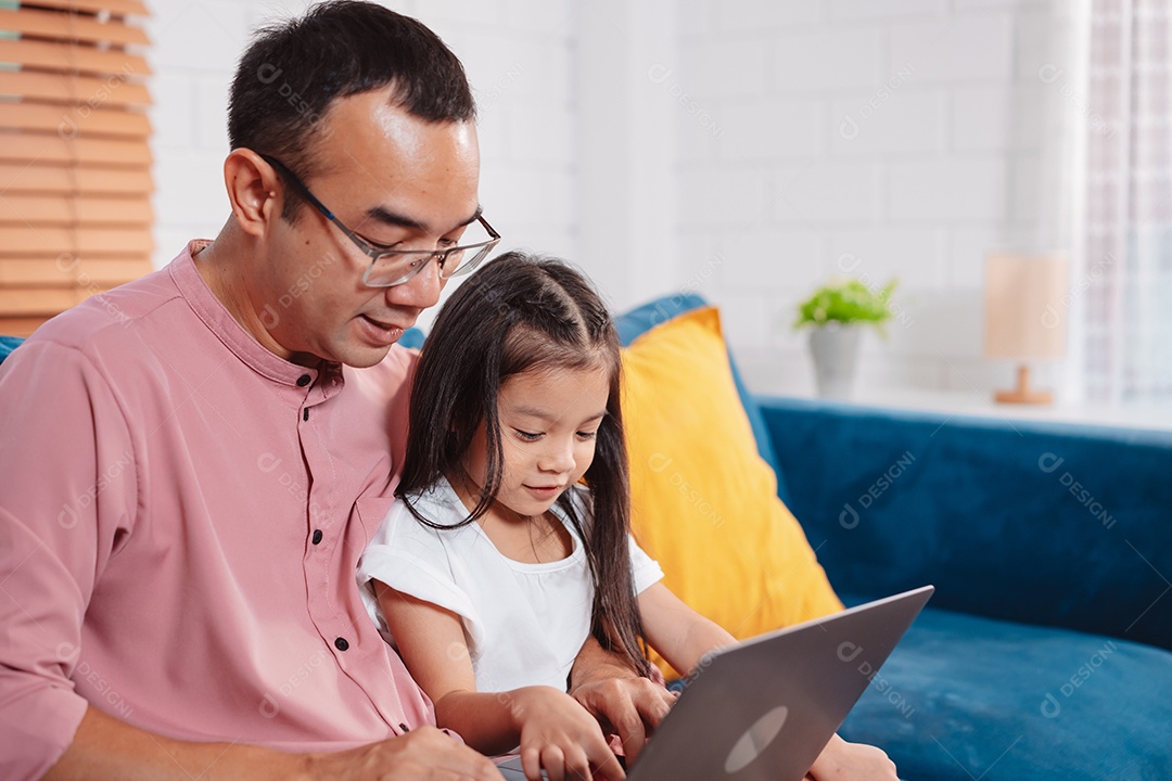 Filha asiática bonitinha com o pai trabalhando no laptop em casa