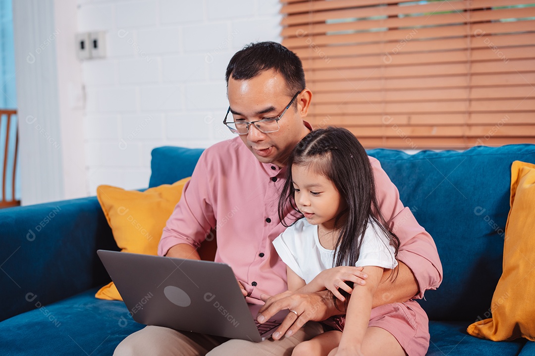 Filha asiática bonitinha com o pai trabalhando no laptop em casa