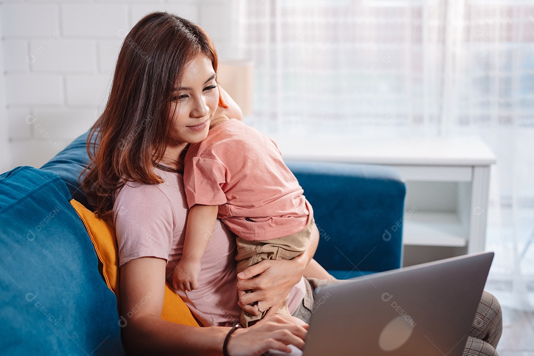 Bonito filho asiático dorme com a mãe trabalhando no laptop em casa.