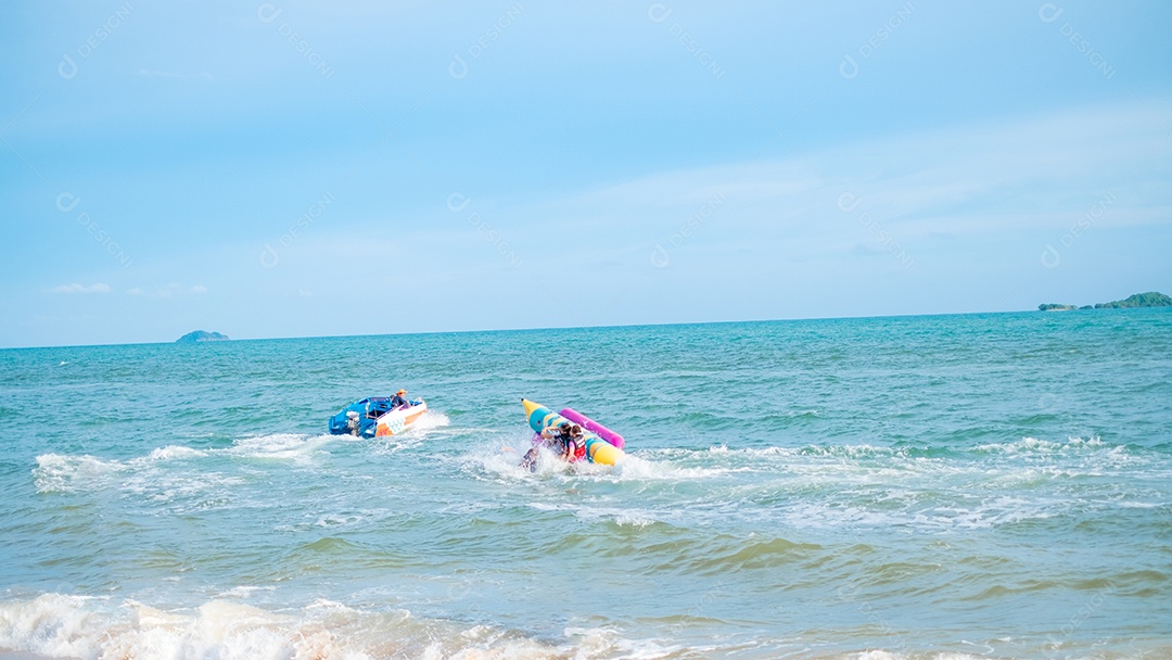 Pessoas andando de banana boat na praia