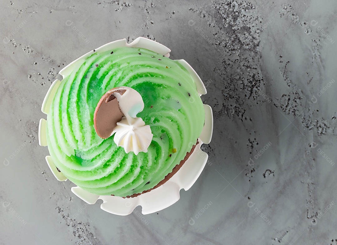 Cupcake com cobertura verde e branca sob fundo isolado
