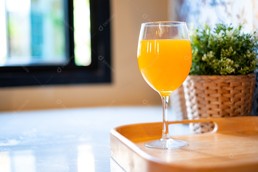 Suco de laranja em uma taça de vinho é colocado sobre a mesa da cozinha.