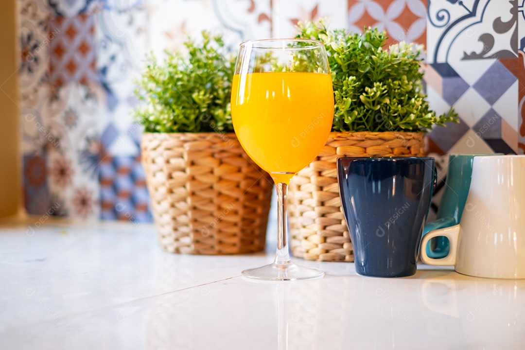 Suco de laranja em uma taça de vinho é colocado sobre a mesa da cozinha.