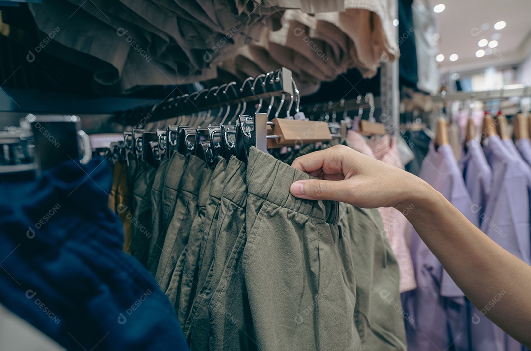 Mulher comprando shorts verdes em loja de roupas