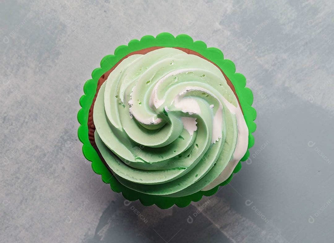 Cupcake com cobertura verde e branca sob fundo isolado