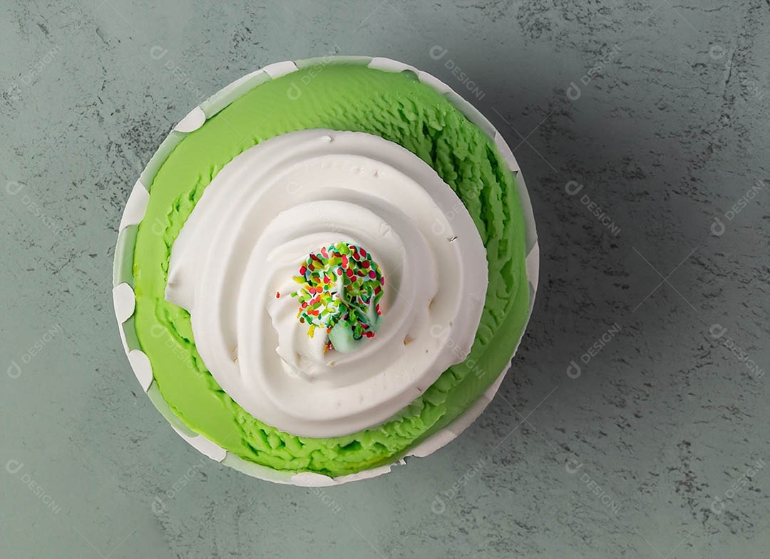 Cupcake com cobertura verde e branca sob fundo isolado