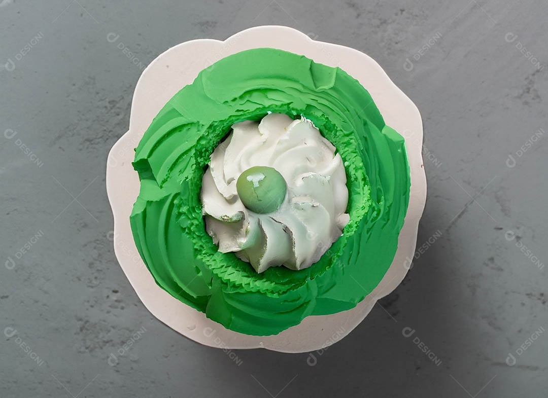 Cupcake com cobertura verde e branca sob fundo isolado