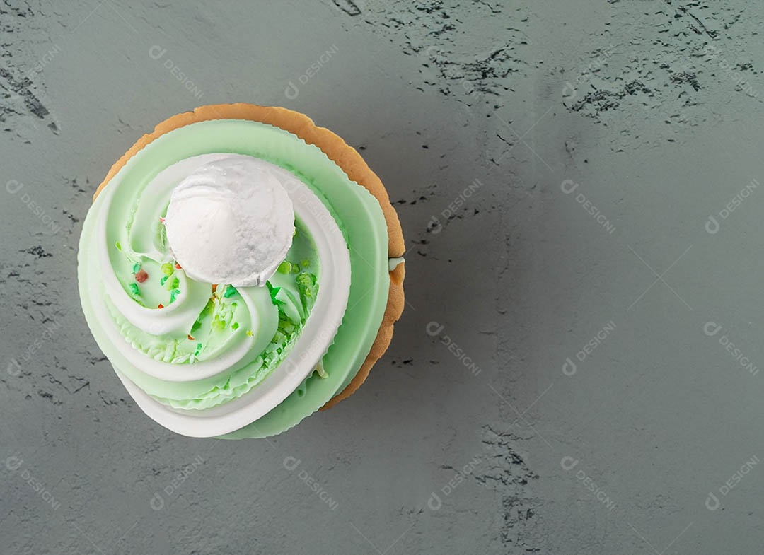 Cupcake com cobertura verde e branca sob fundo isolado