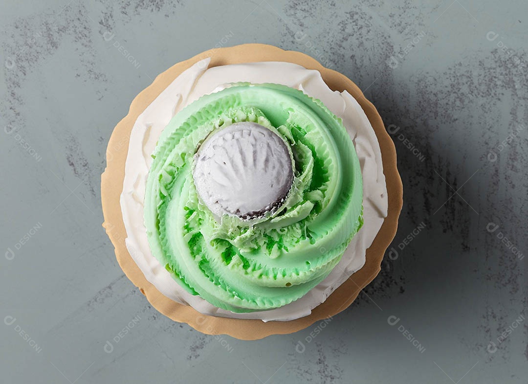 Cupcake com cobertura verde e branca sob fundo isolado