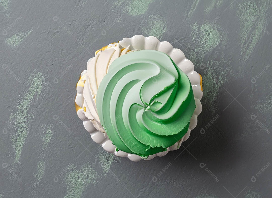 Cupcake com cobertura verde e branca sob fundo isolado