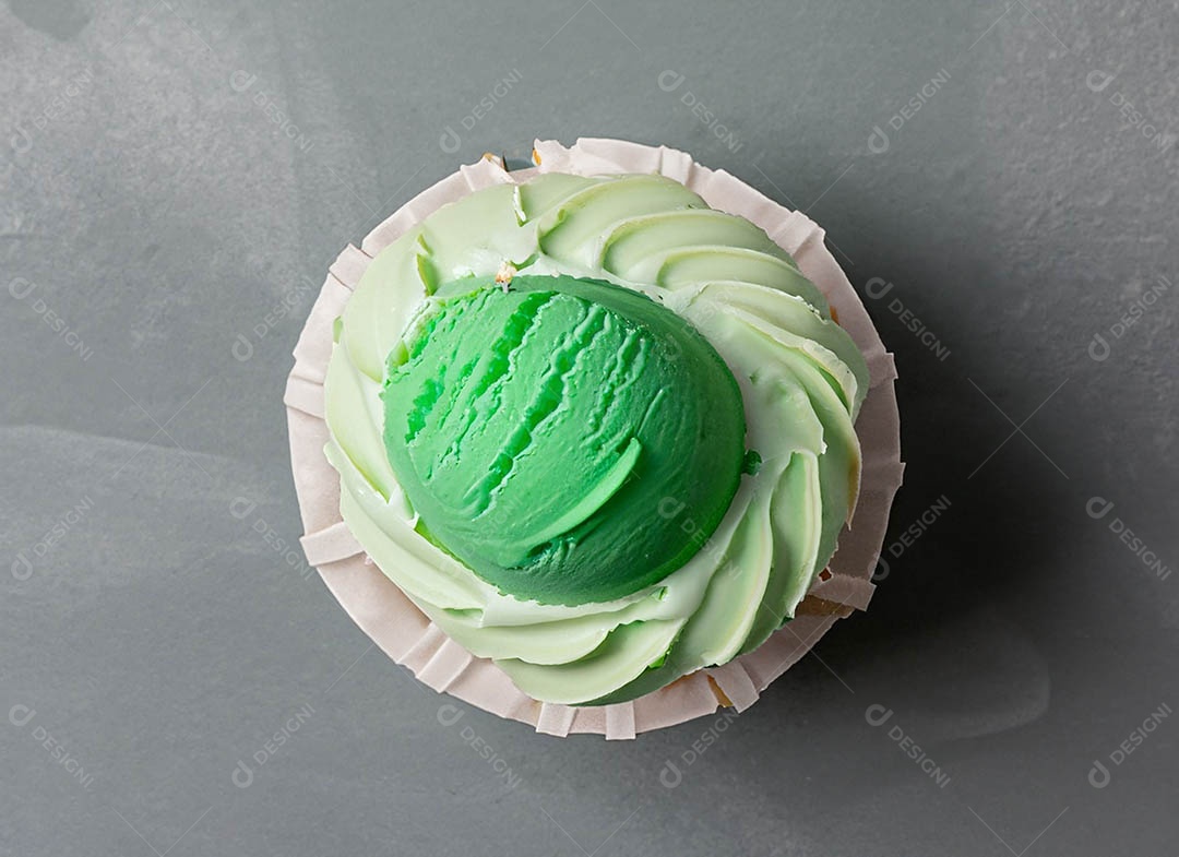Cupcake com cobertura verde e branca sob fundo isolado
