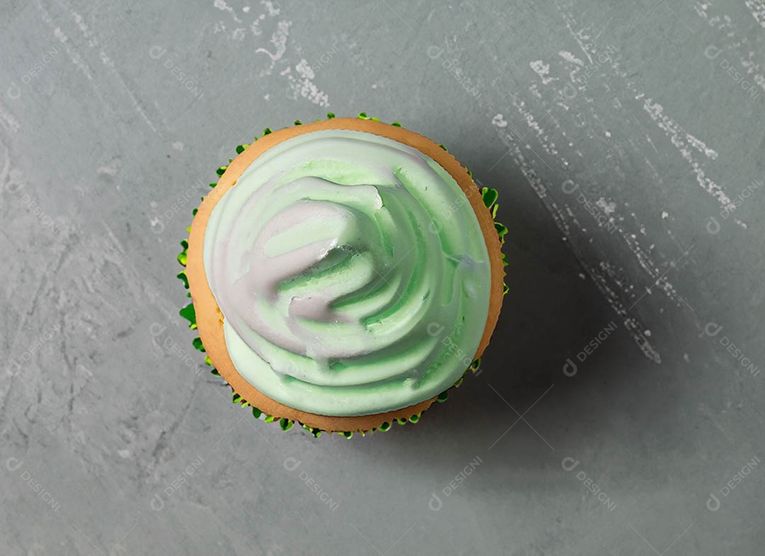 Cupcake com cobertura verde e branca sob fundo isolado