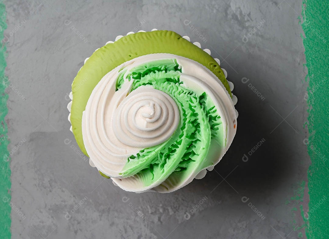 Cupcake com cobertura verde e branca sob fundo isolado
