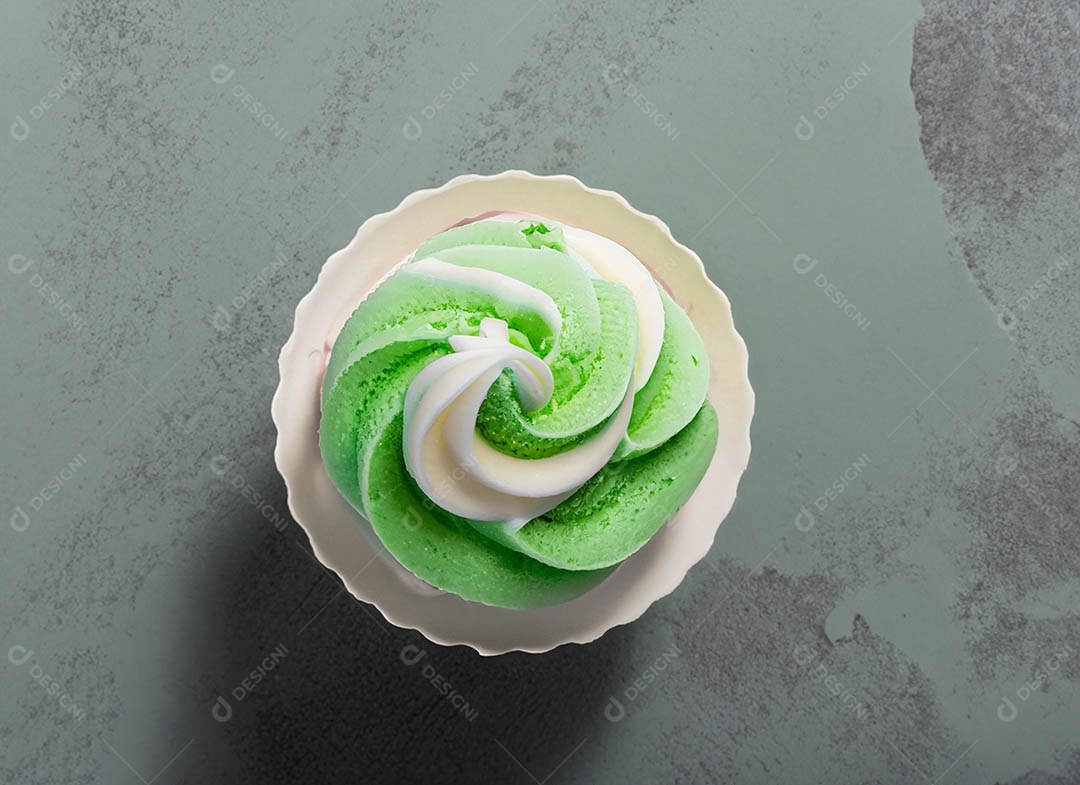 Cupcake com cobertura verde e branca sob fundo isolado