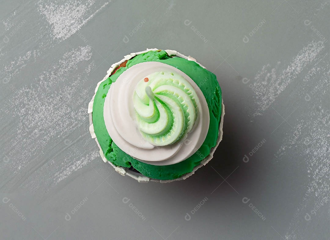 Cupcake com cobertura verde e branca sob fundo isolado
