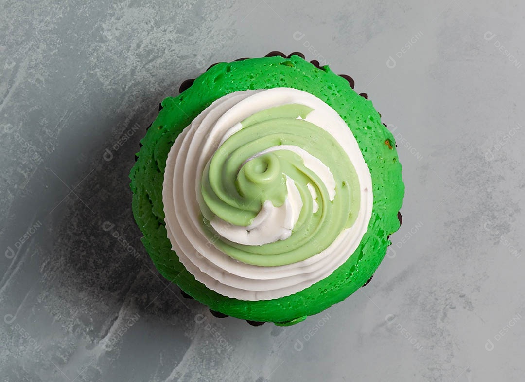 Cupcake com cobertura verde e branca sob fundo isolado