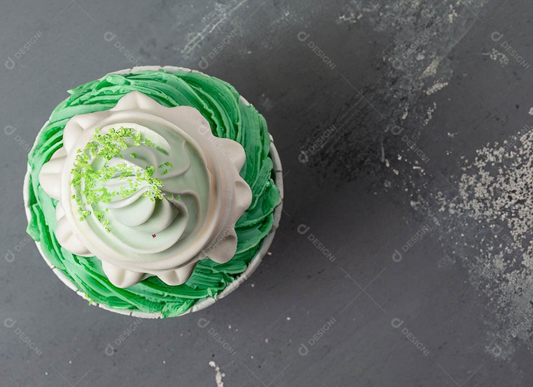 Cupcake com cobertura verde e branca sob fundo isolado