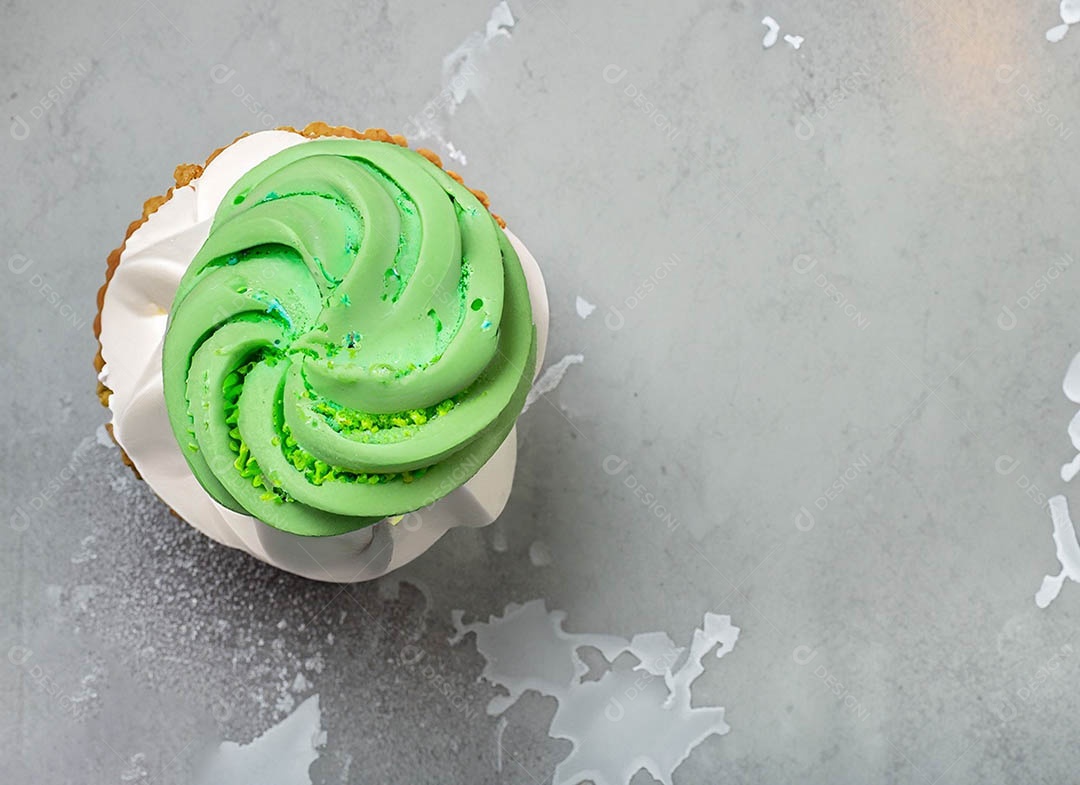 Cupcake com cobertura verde e branca sob fundo isolado