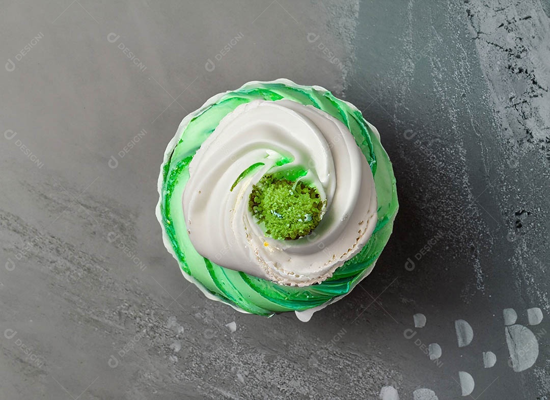 Cupcake com cobertura verde e branca sob fundo isolado