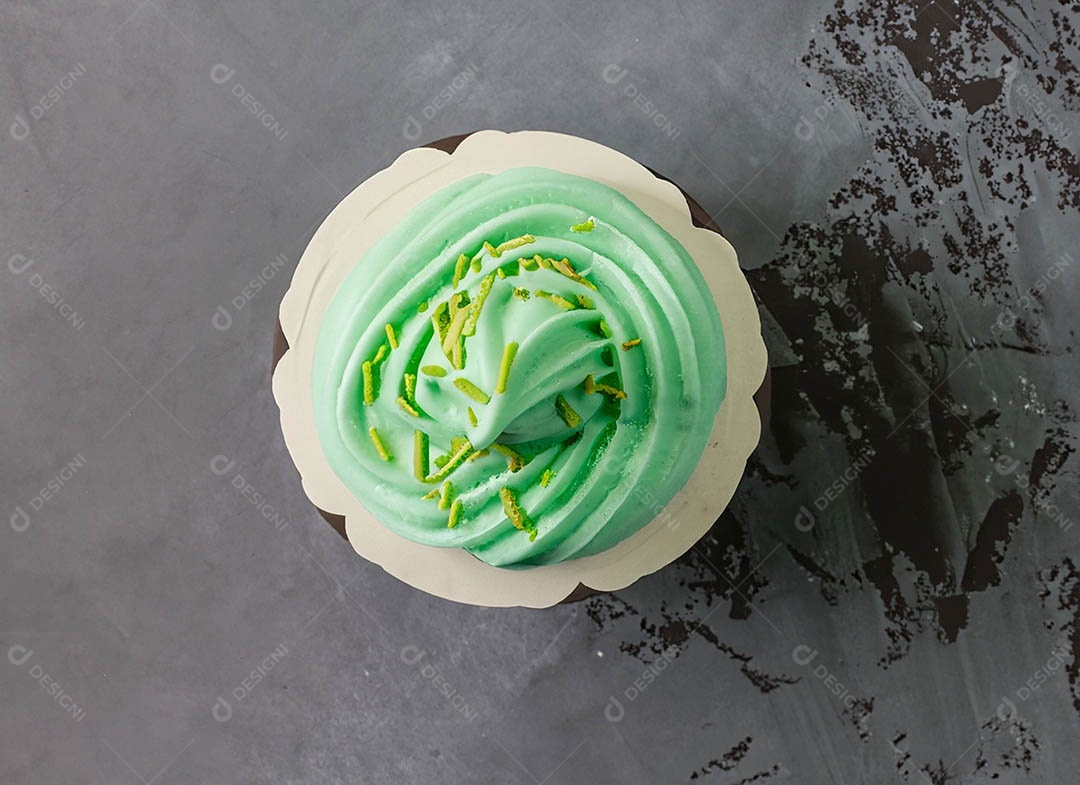 Cupcake com cobertura verde e branca sob fundo isolado