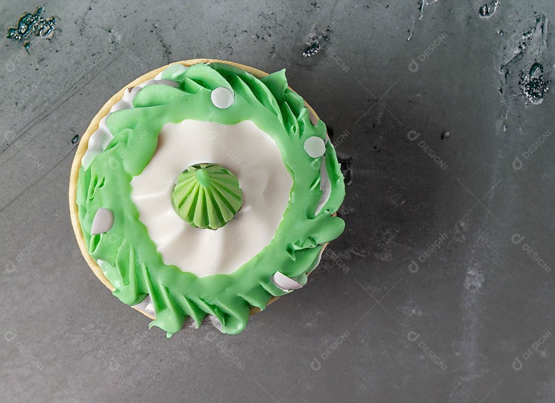 Cupcake com cobertura verde e branca sob fundo isolado