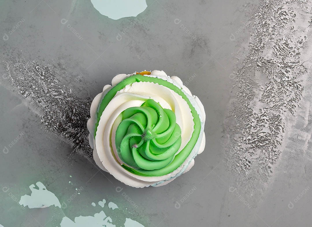 Cupcake com cobertura verde e branca sob fundo isolado
