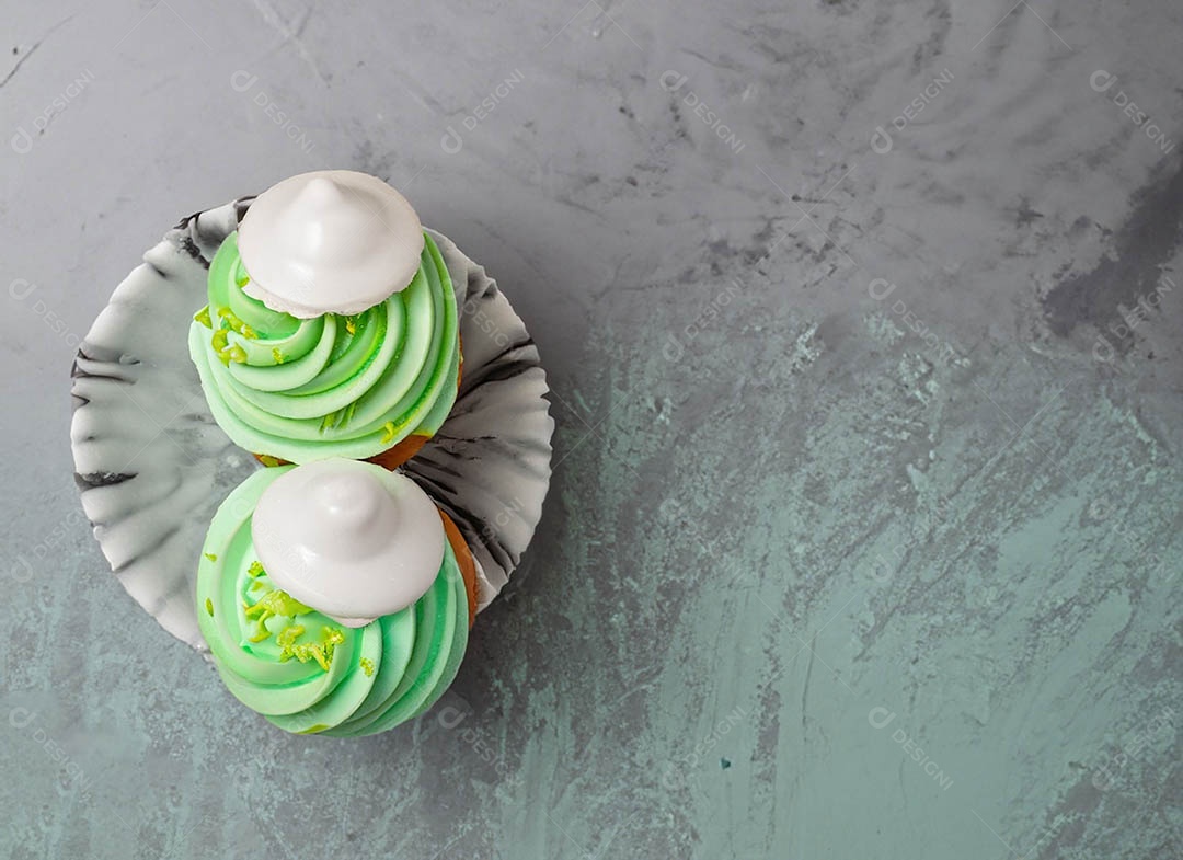 Cupcake com cobertura verde e branca sob fundo isolado
